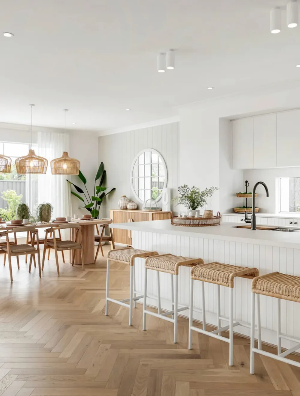light open-concept kitchen with white island, woven stools, and dining area