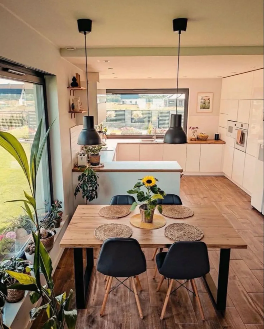 open-concept kitchen with wood dining table, plants, and light cabinetry