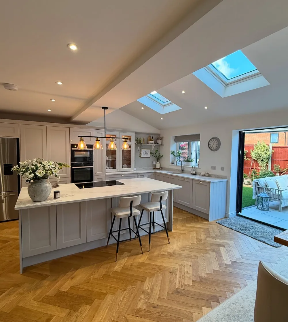 open-concept kitchen with light cabinetry, island, skylights, and garden doors