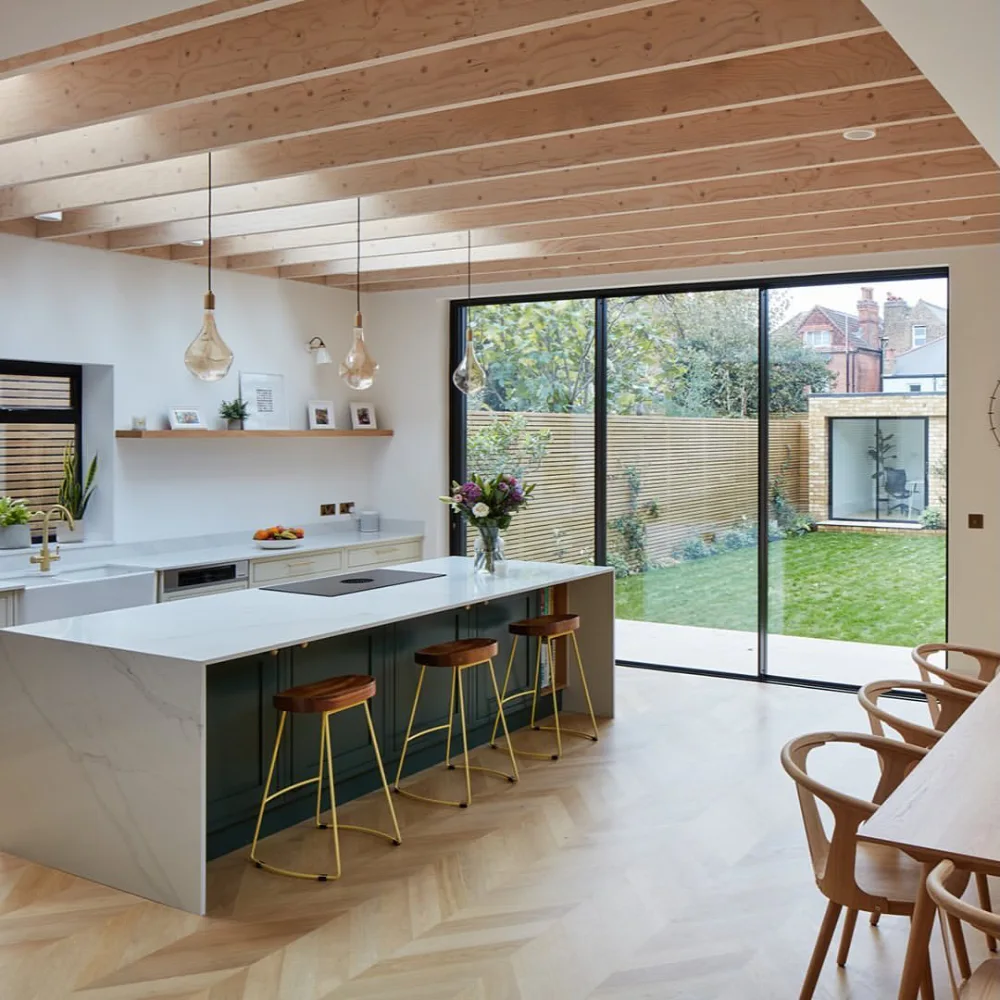 open-concept kitchen with dark island and large glass doors overlooking a garden