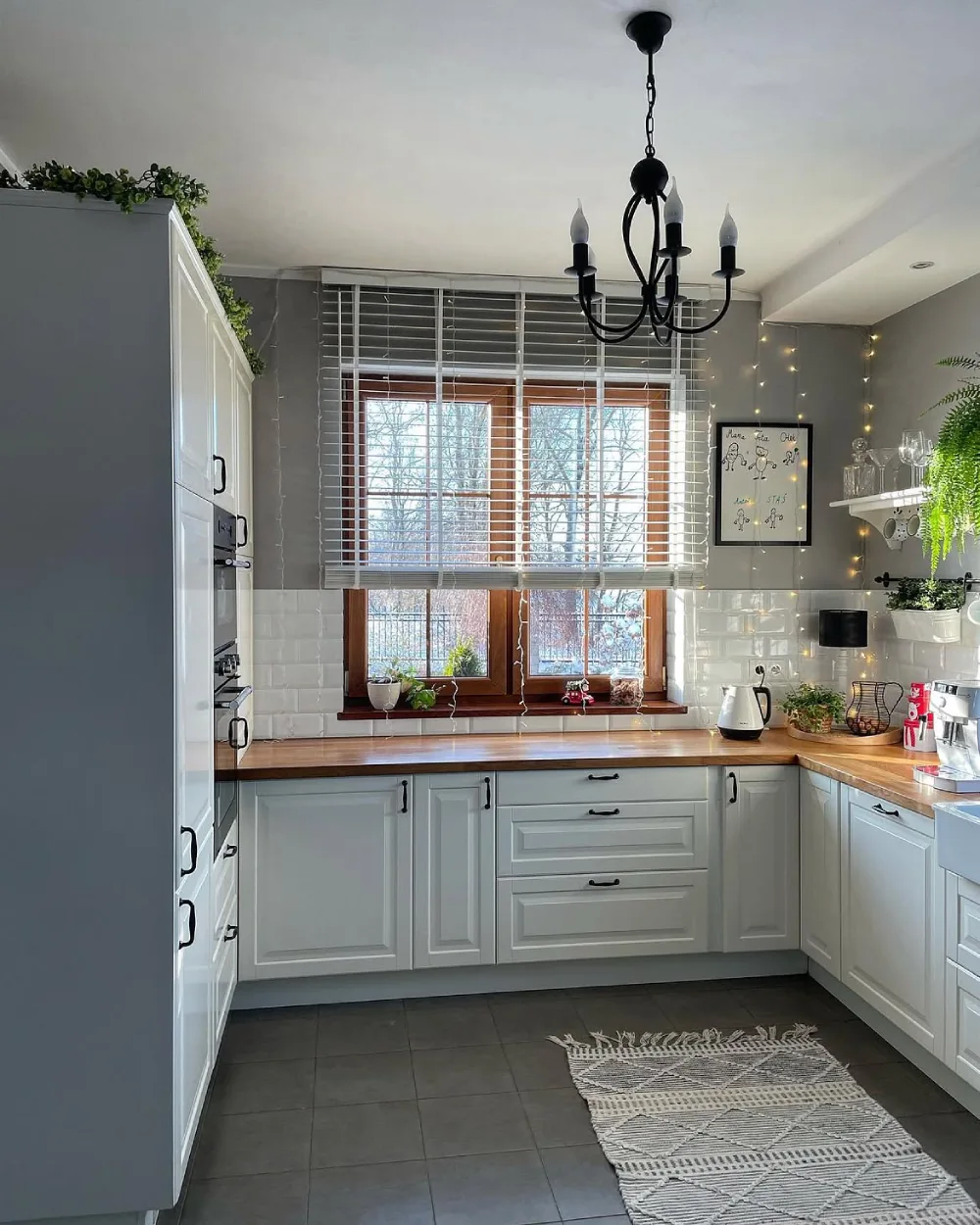 Compact kitchen with white cabinets, wood countertops, and large windows
