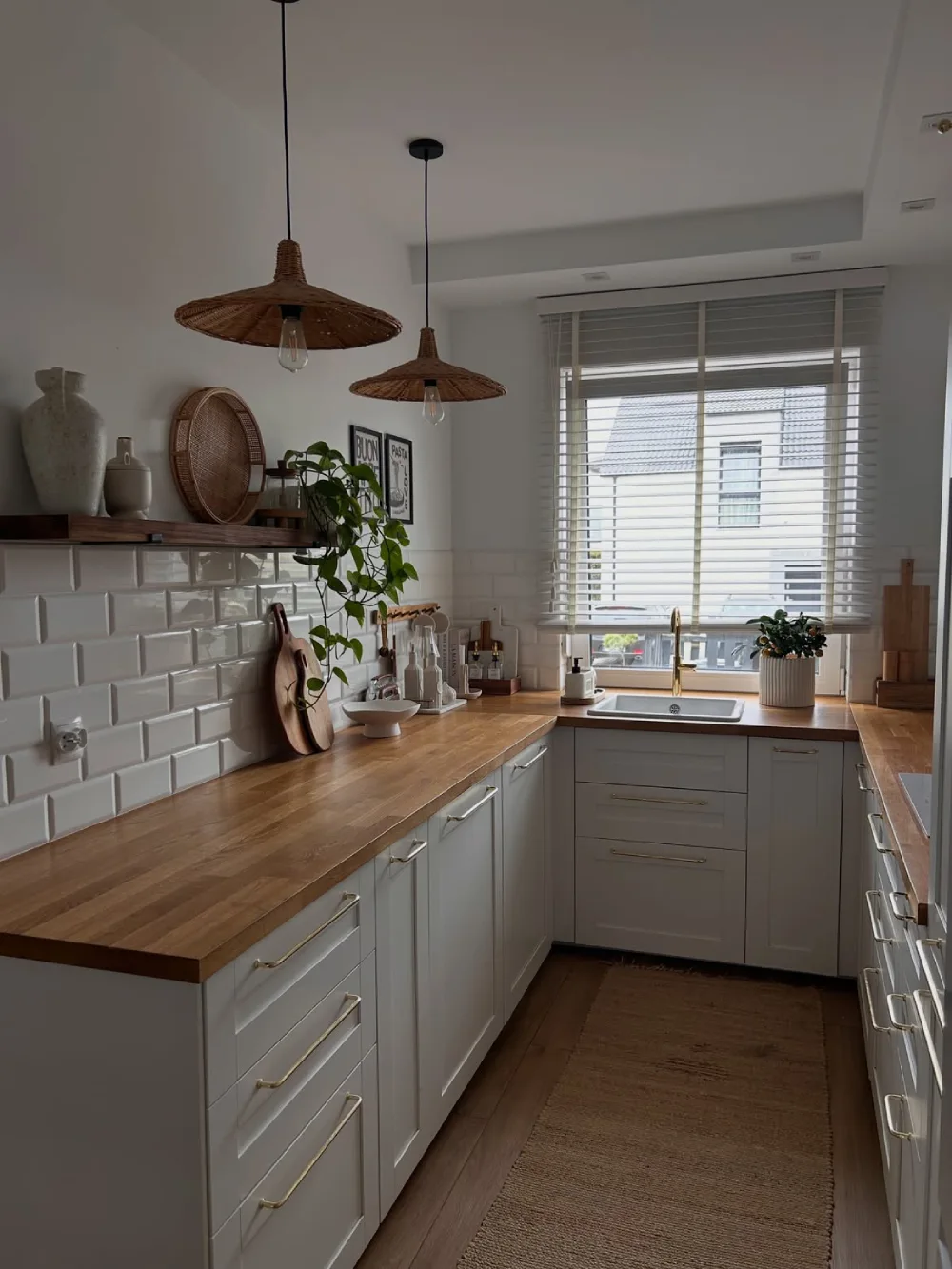 Narrow galley kitchen with dark lower cabinets, patterned backsplash, and a long runner