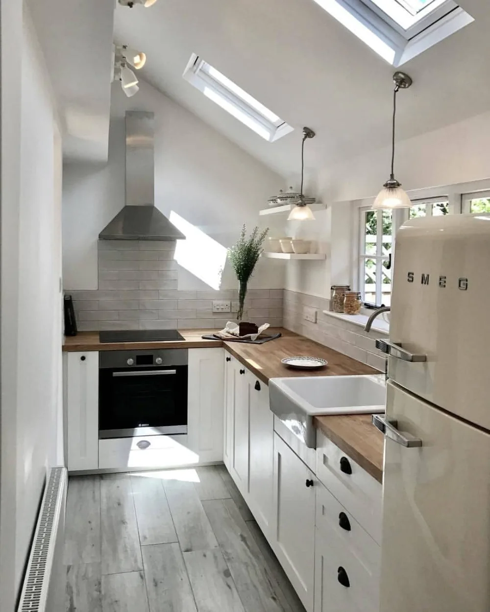 Bright compact kitchen with white cabinets, wood counters, and multiple skylights