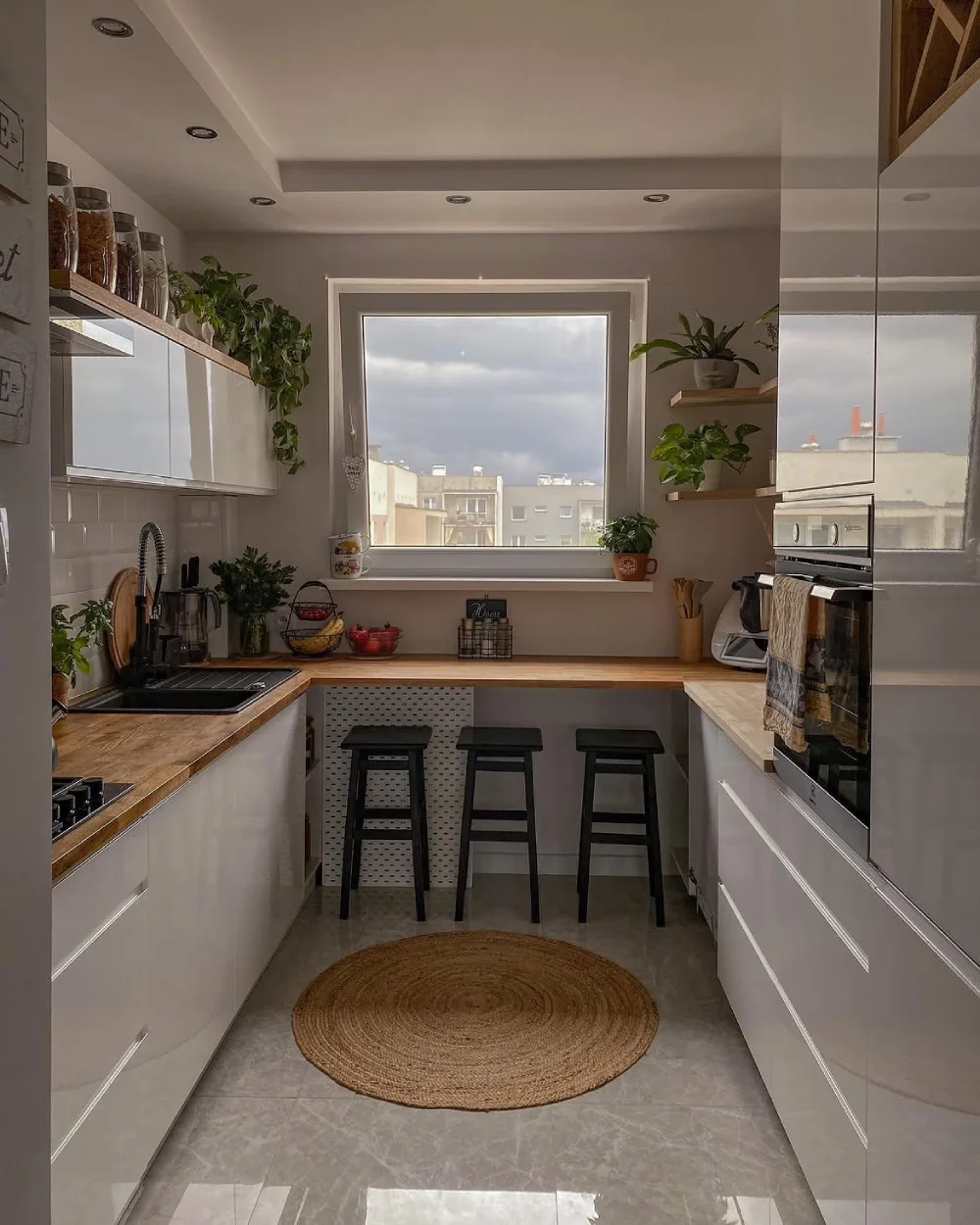 white galley kitchen with wood countertops, breakfast bar, and three black stools