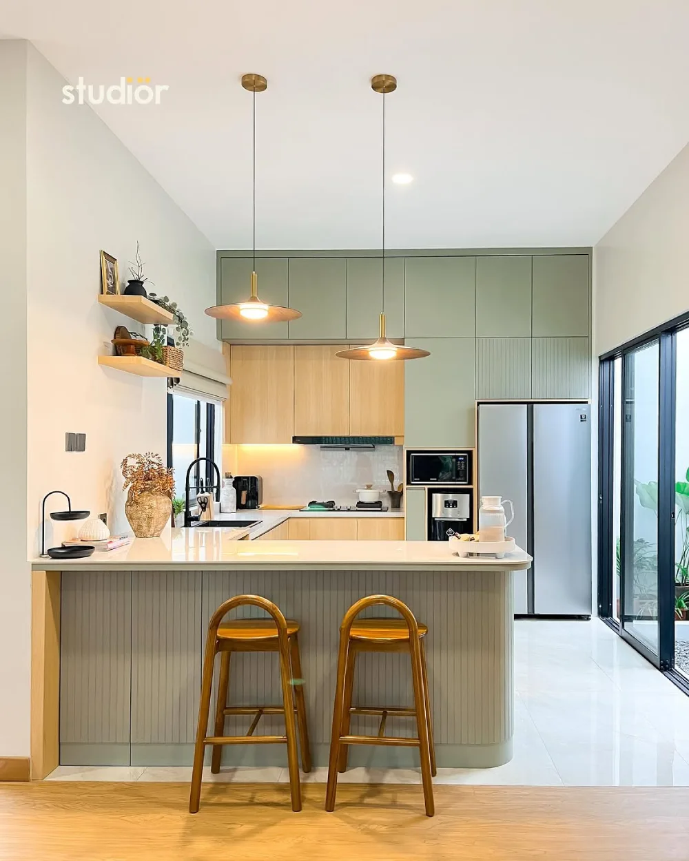 sage green and wood kitchen with peninsula, pendant lights, and bar stools