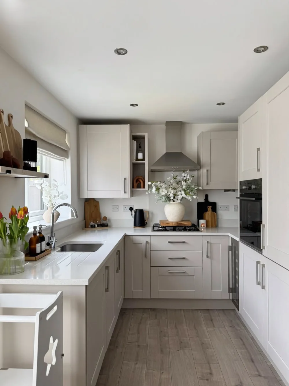 bright white kitchen with farmhouse sink, white cabinets, and wood flooring
