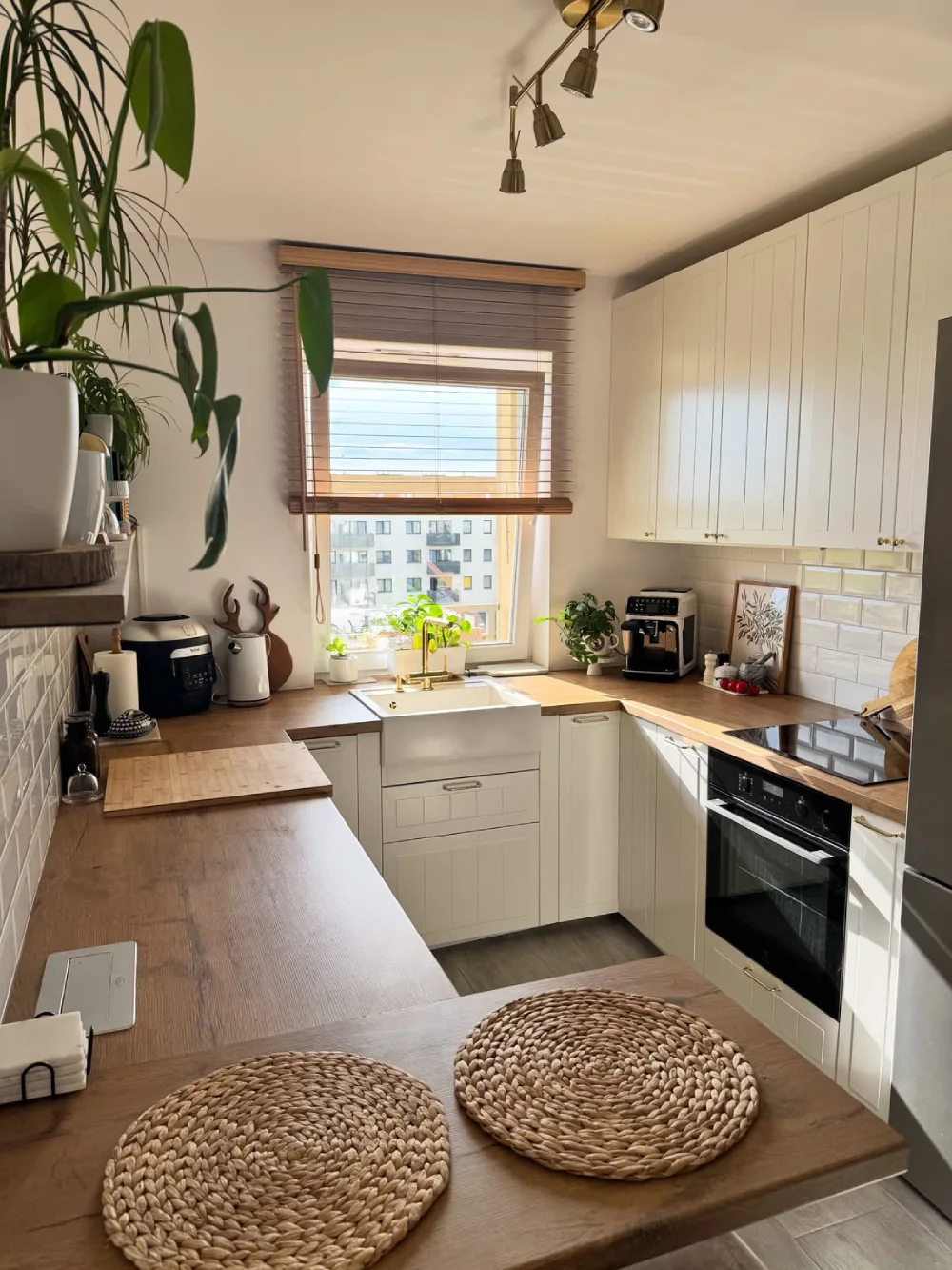 white kitchen with wood countertops, woven placemats, and window blinds
