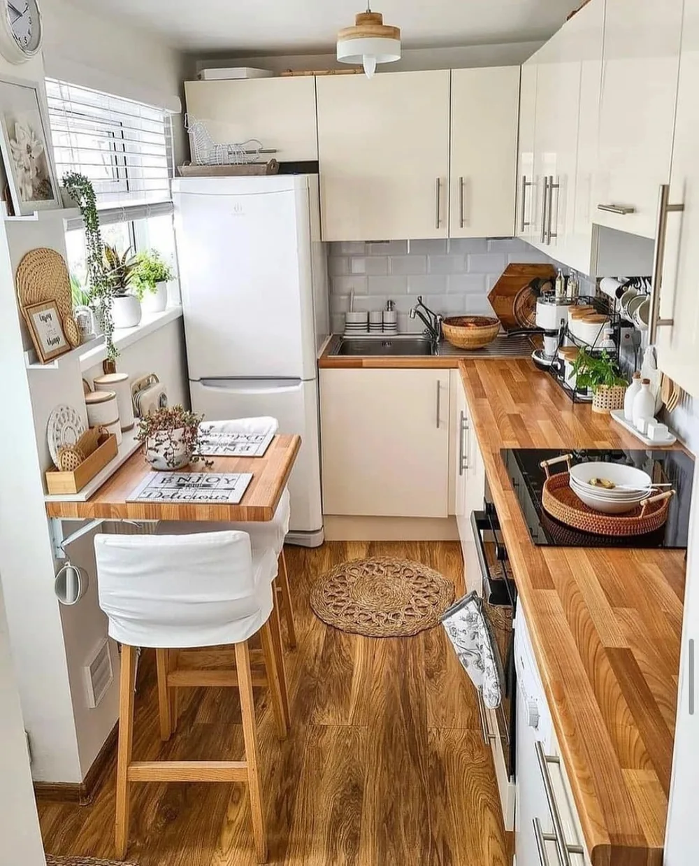 small white kitchen with butcher block countertops, breakfast table, and woven rug