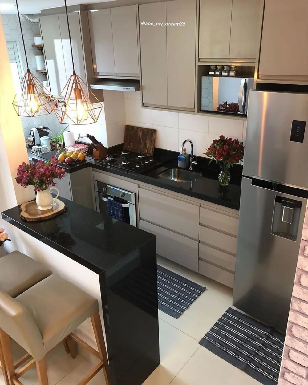 white kitchen with black countertops, copper pendant lights, and stainless steel refrigerator