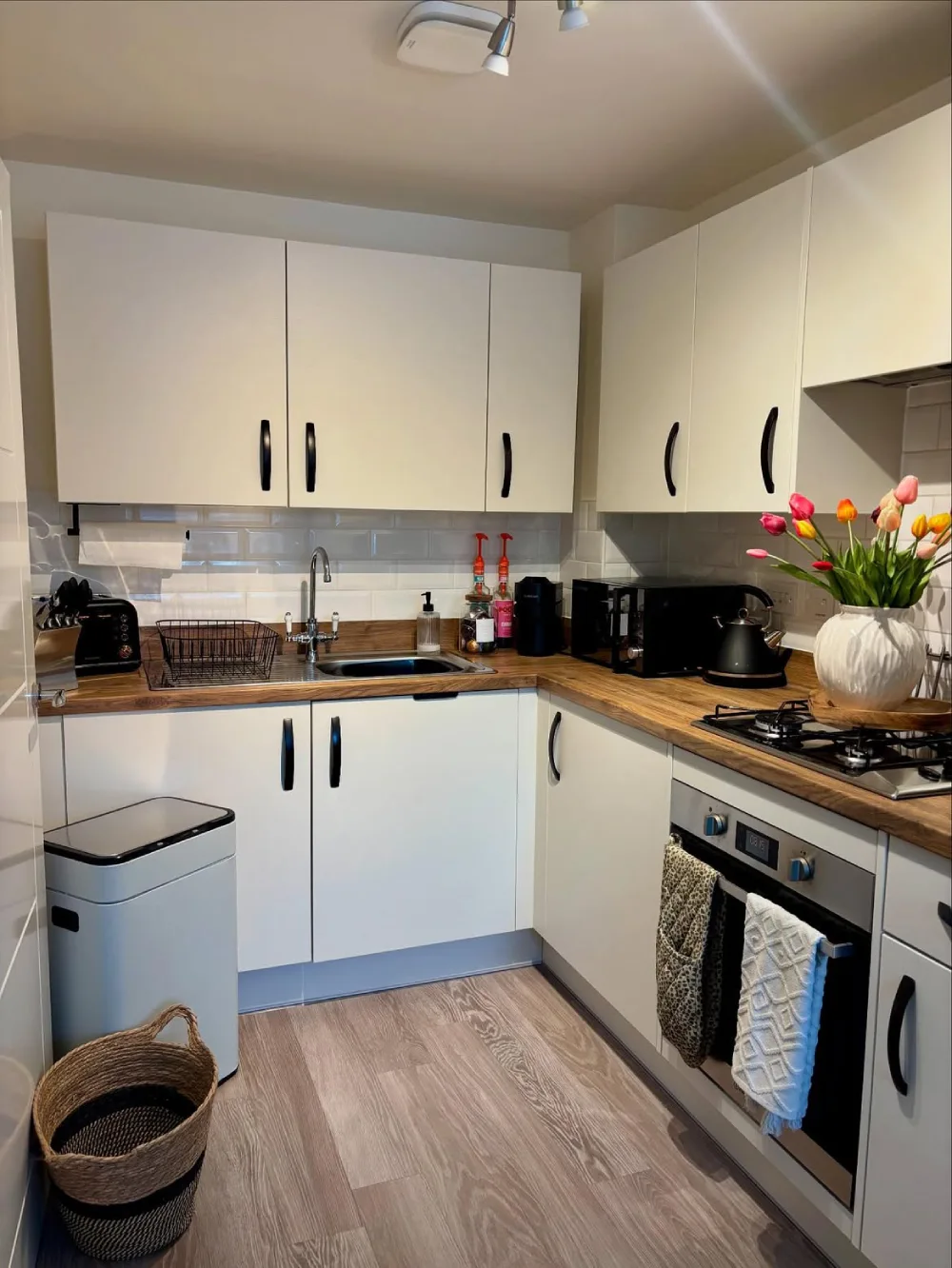 white shaker kitchen with wood countertops, subway tile, and fresh flowers