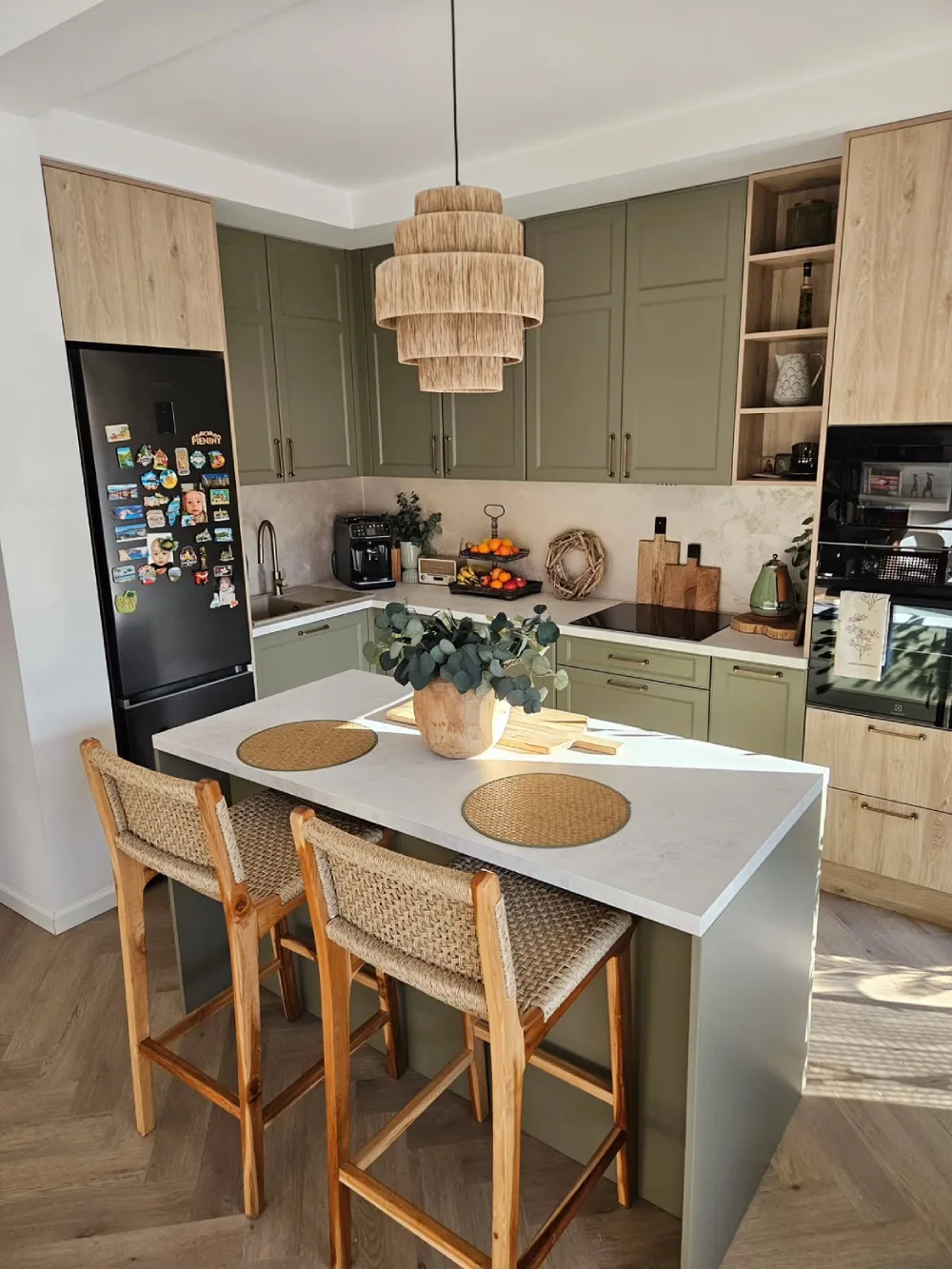 Small green kitchen with a compact island and woven bar stools