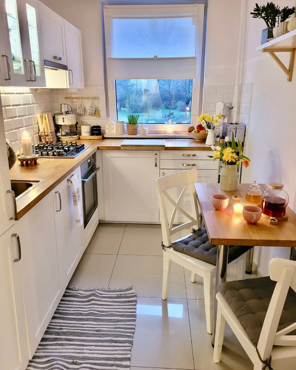 Cozy small kitchen with white cabinets, wood counters, and a compact dining table