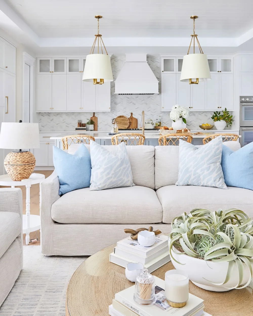 Light coastal living room with white sofa, pale blue pillows, rattan chairs, and natural textures