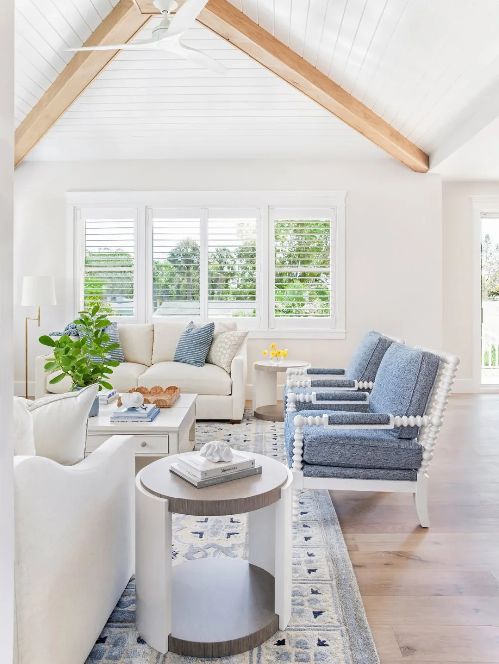 Airy coastal living room with white vaulted ceiling, natural wood beams, and blue accents