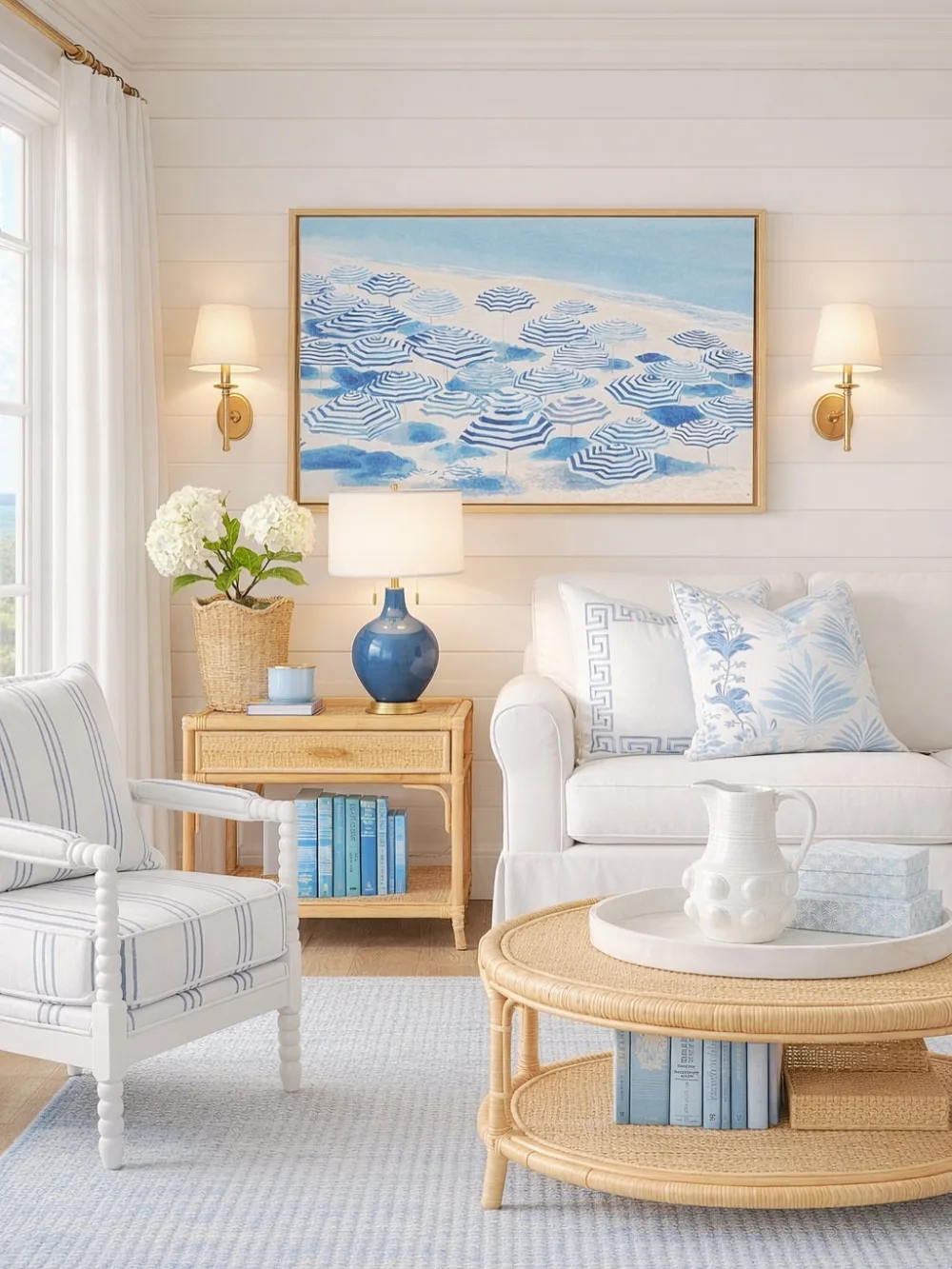 Coastal living room with white shiplap walls, blue beach artwork, rattan tables, and striped seating