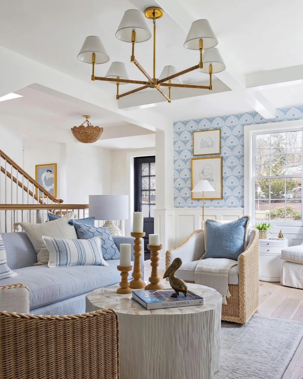 Coastal living room with blue and white seating, woven rattan furniture, and patterned wallpaper