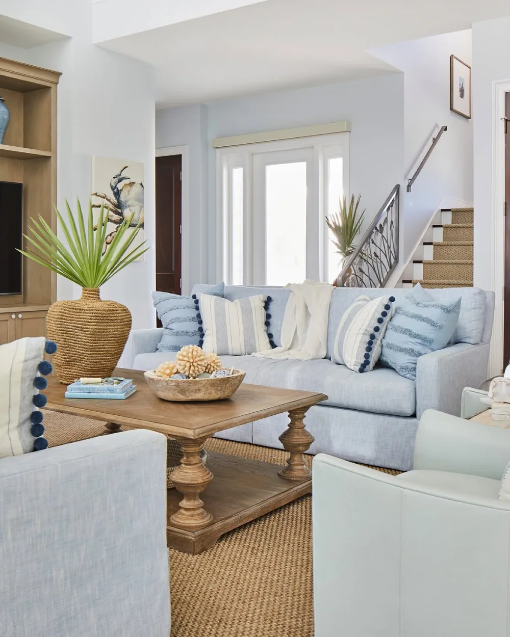 Coastal living room with pale blue sofa, striped pillows, woven rug, and natural wood coffee table