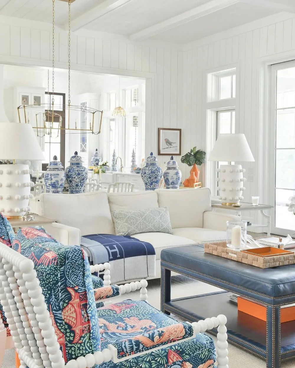 Blue and white coastal living room with patterned chairs, white sofa, and decorative blue accents