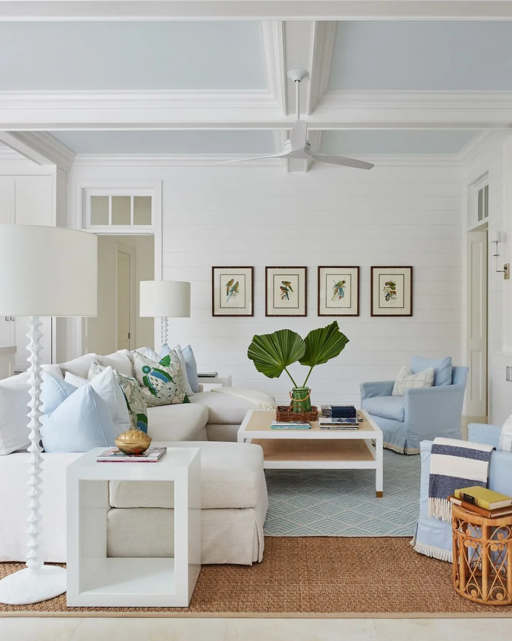 Airy coastal living room with white seating, blue pillows, woven coffee table, and natural textures