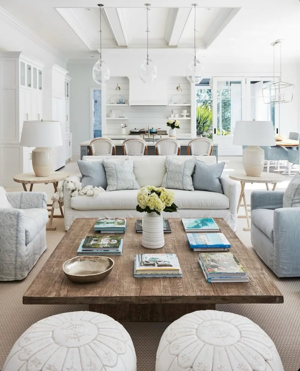 Bright coastal living room with white sofa, large wood coffee table, blue pillows, and natural textures