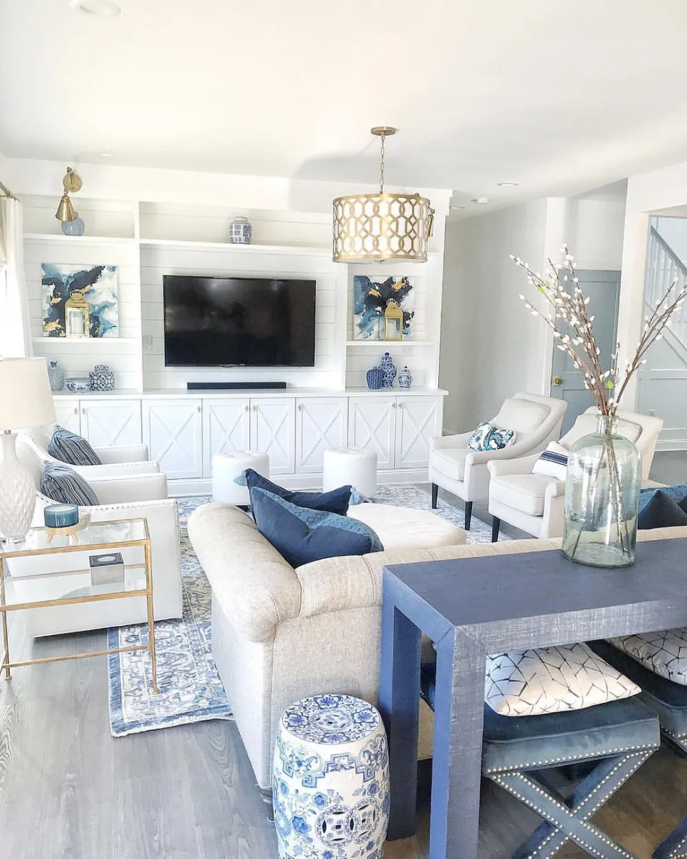 Bright white coastal living room with navy blue accents, built-in cabinets, and woven decor