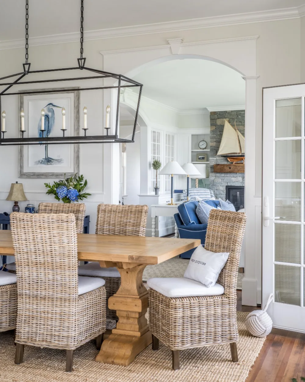 Coastal dining area with woven rattan chairs, a natural wood table, and blue and white decor