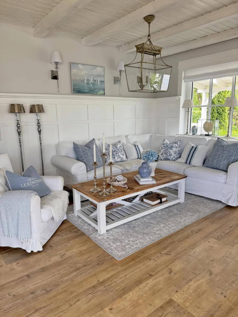 Coastal living room with white sectional sofa, blue pillows, wood coffee table, and natural flooring