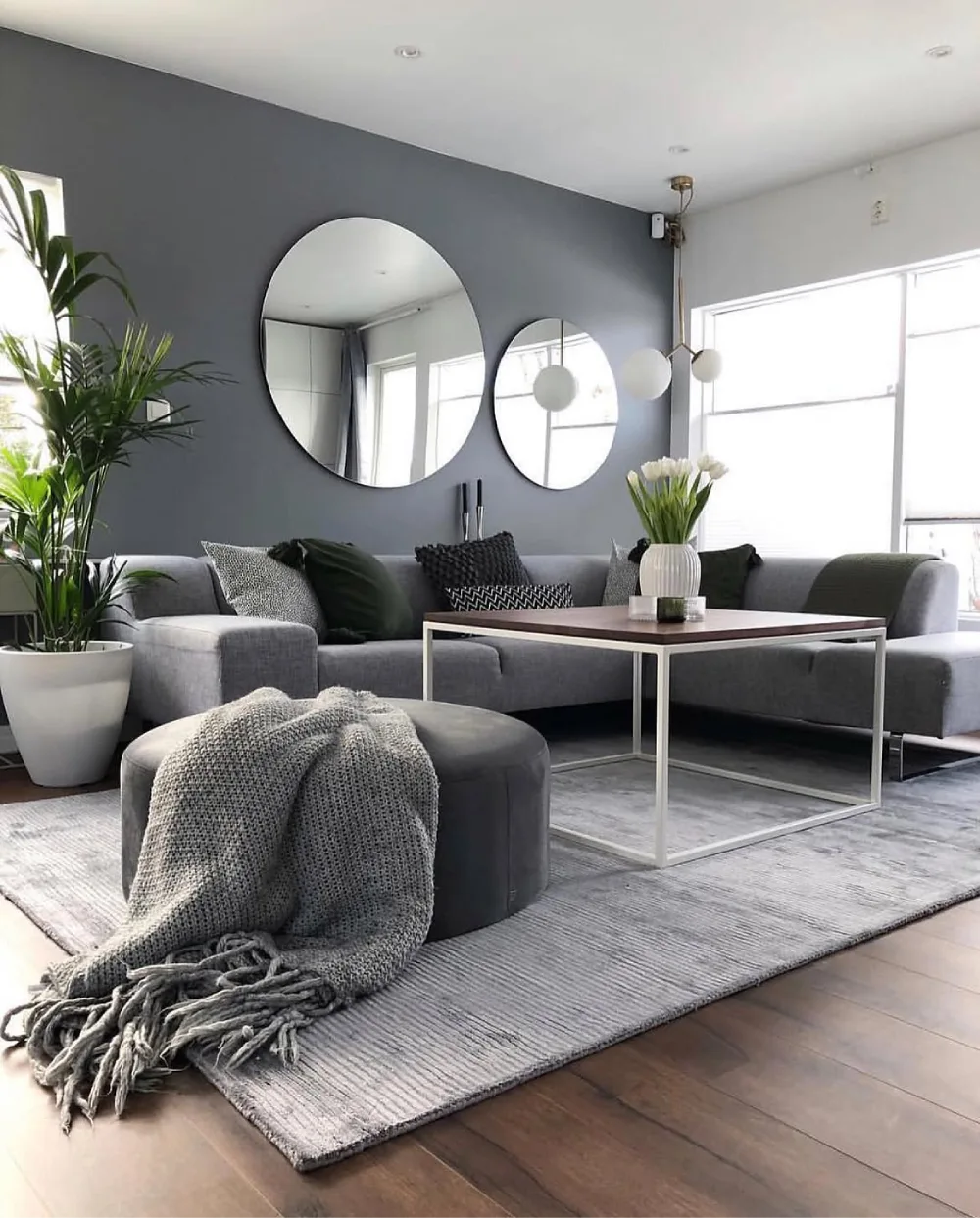 Gray sectional sofa in a modern living room with black accent wall and white decor
