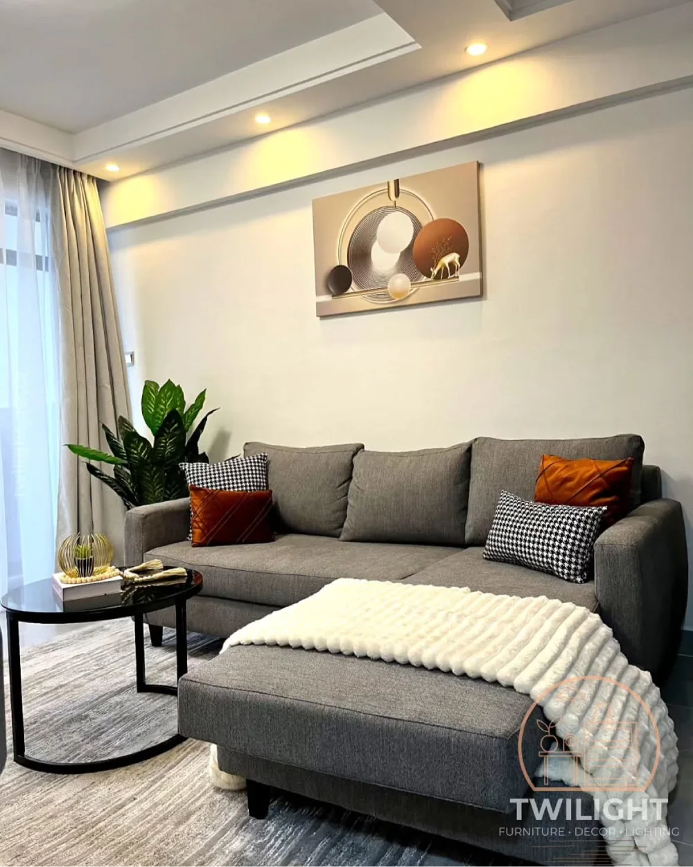Gray sectional with rust orange pillows, black accents, and a soft white throw