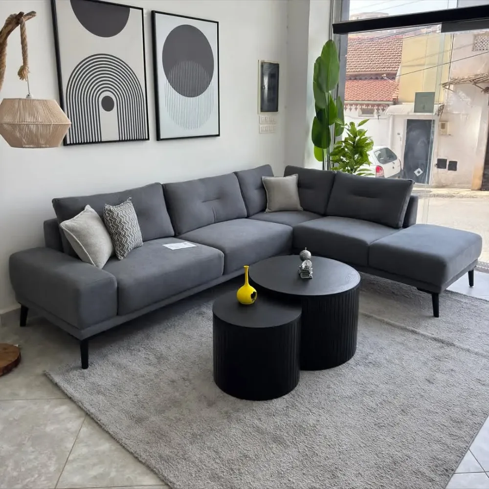 Gray sectional sofa with black coffee tables, modern artwork, and neutral decor