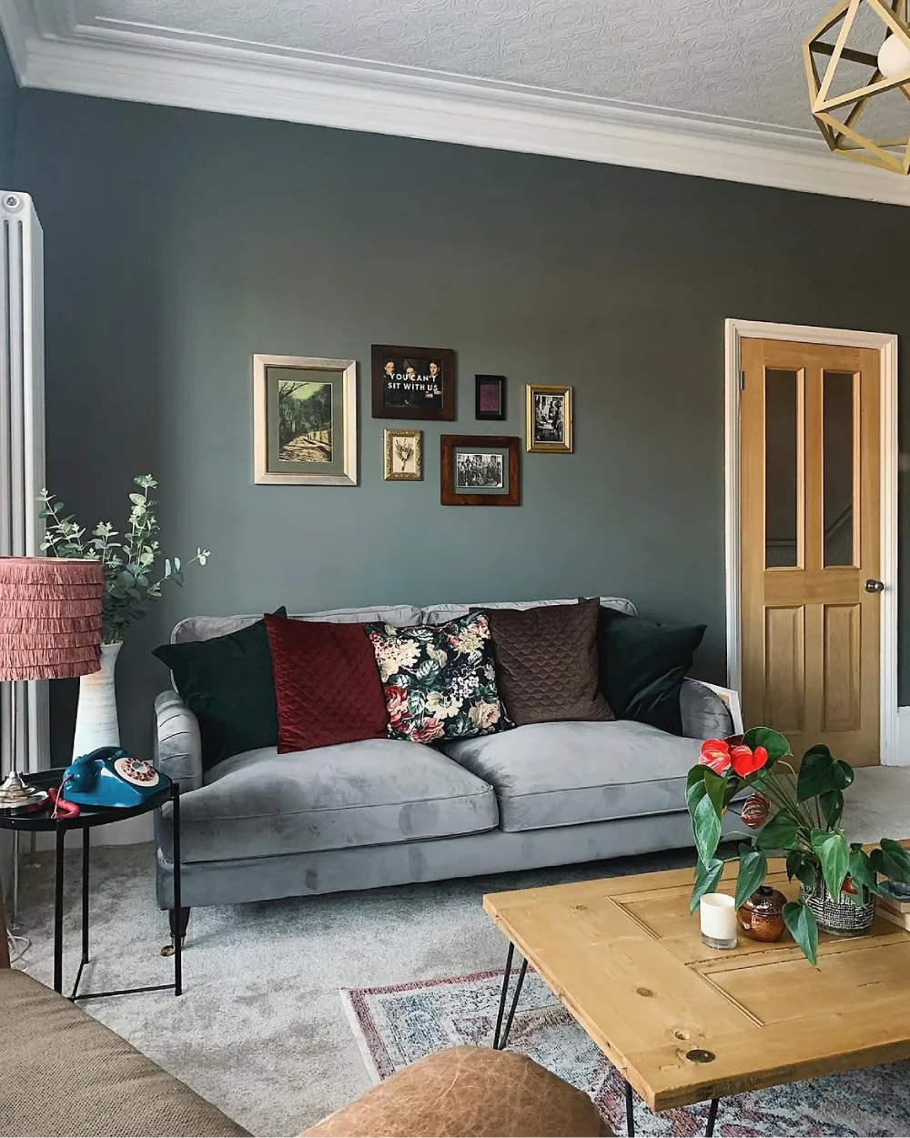 Light gray sofa against a dark green accent wall with colorful pillows and plants