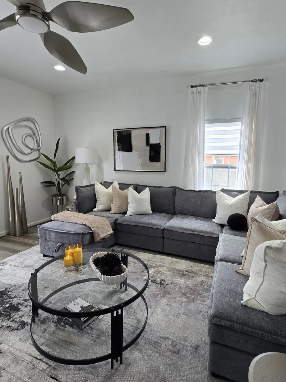 Dark gray sectional with cream pillows, abstract art, and a round black coffee table