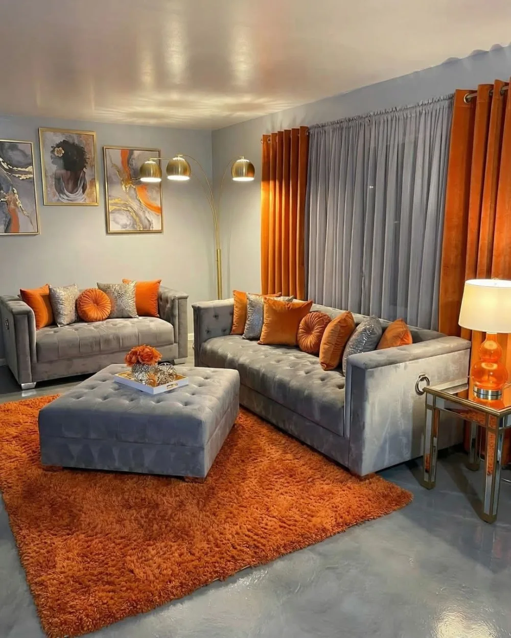Gray tufted sofas styled with orange pillows and a bright orange shag rug