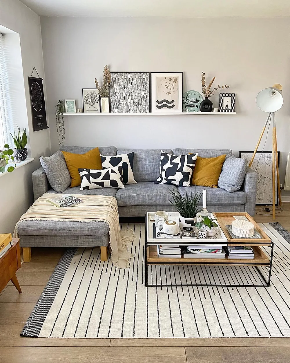 Gray sofa with mustard yellow pillows and black and white patterned accents in a cozy living room