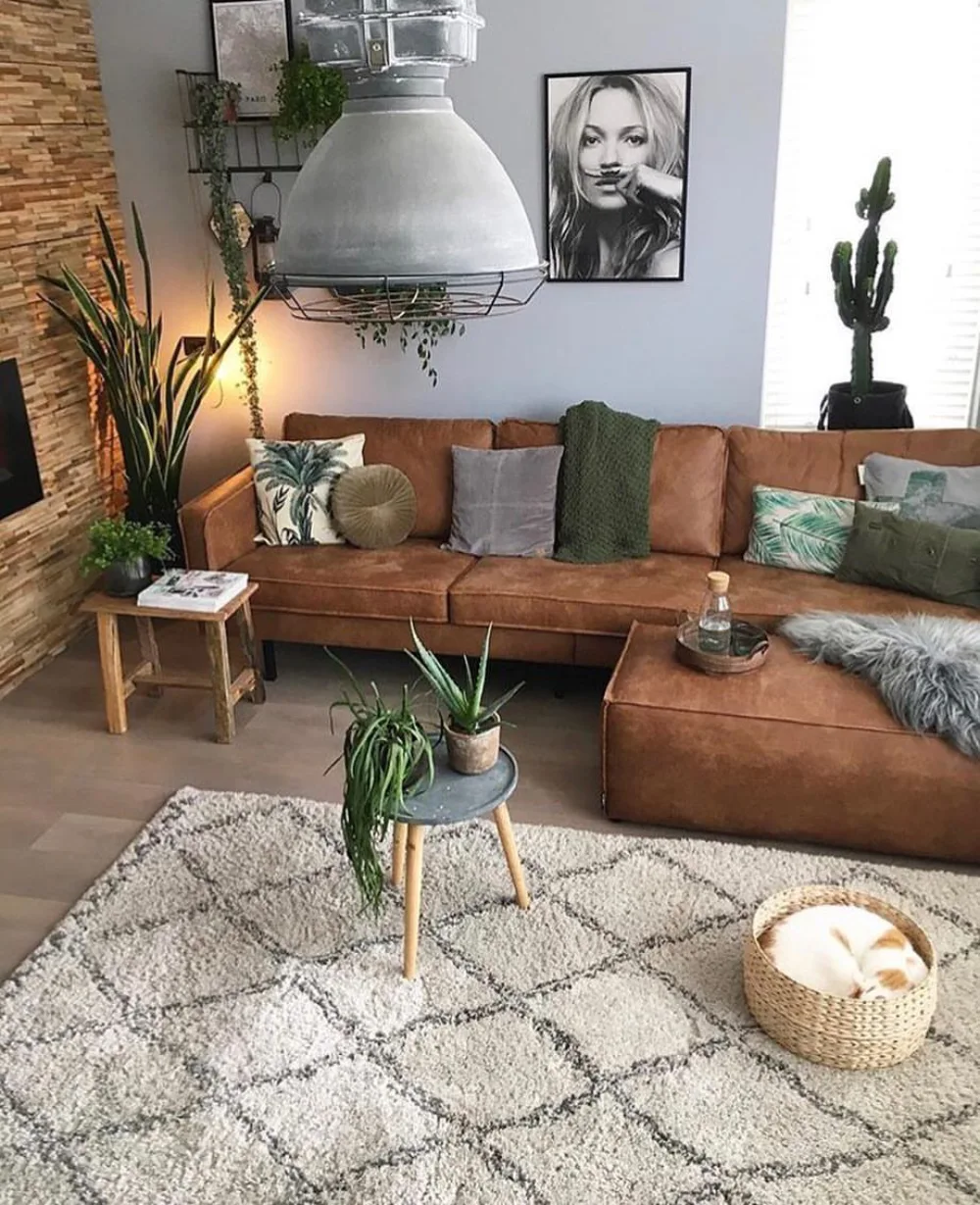Brown sectional sofa with green pillows, houseplants, and a soft geometric rug