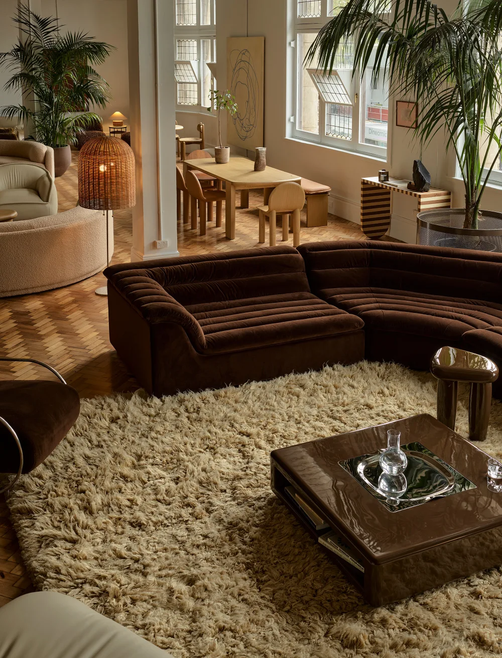 Dark brown sectional with a textured cream rug and glossy brown coffee table