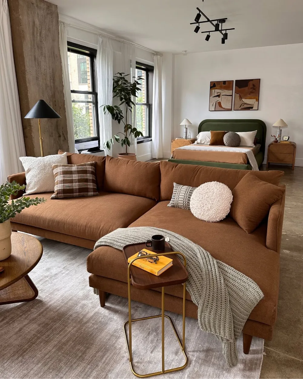 Warm brown sectional sofa with earthy green bedroom accents and neutral decor