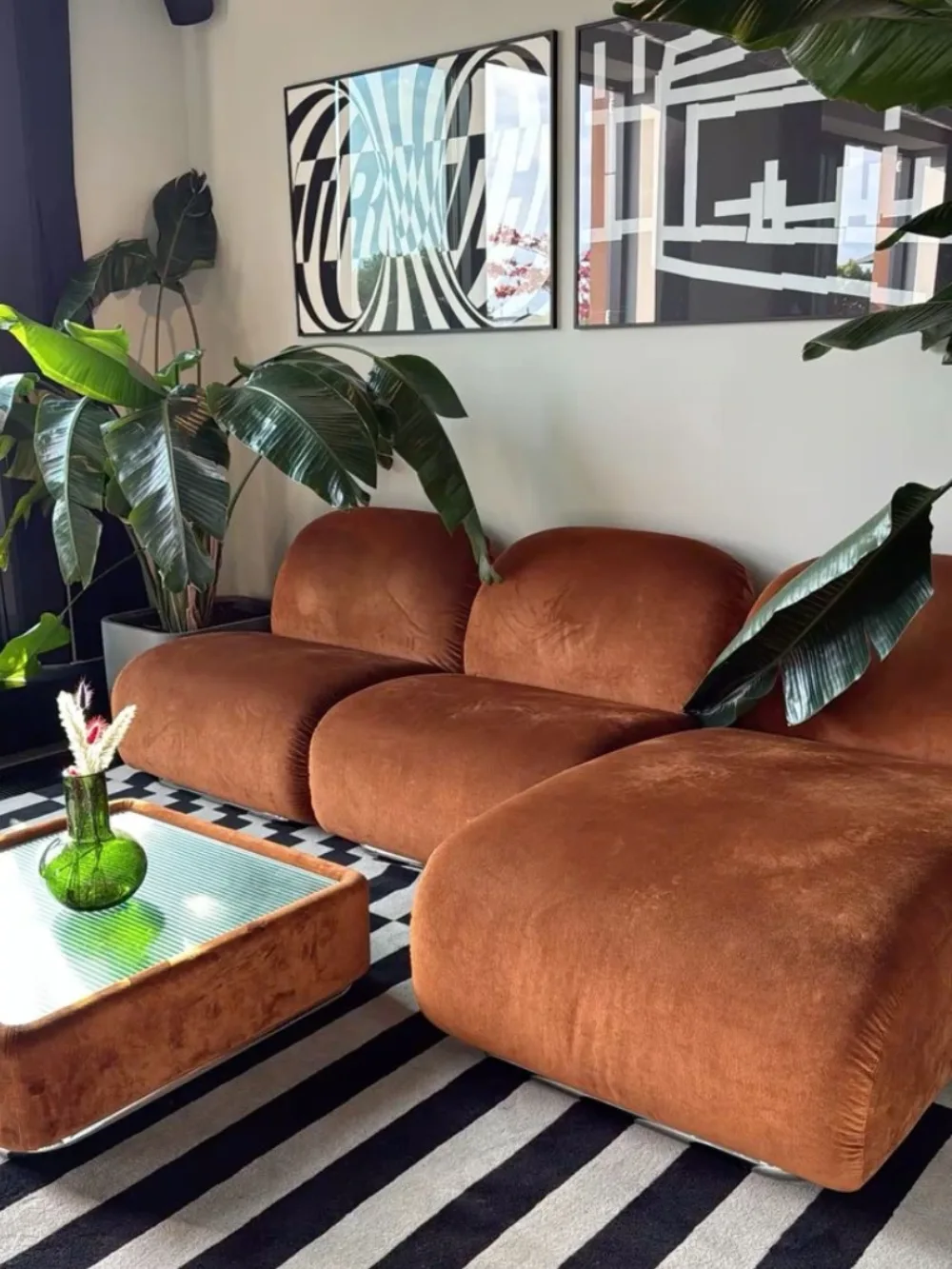Cognac brown sectional sofa with tropical plants and bold black and white striped rug
