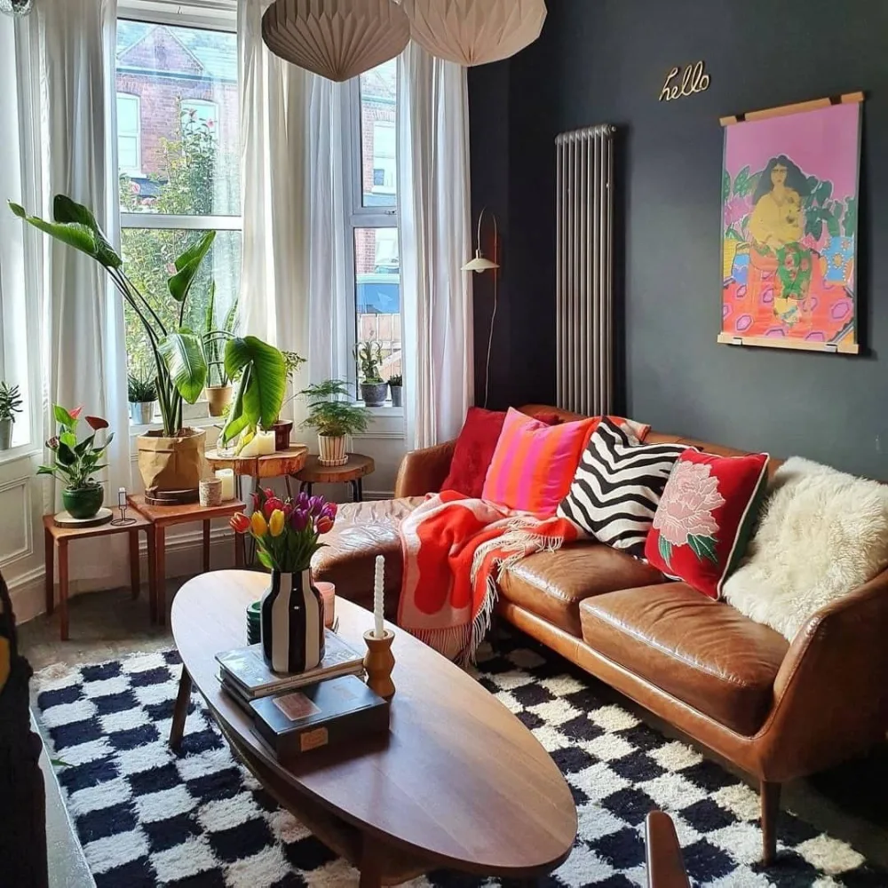 Brown leather sofa with colorful patterned pillows, houseplants, and a black and white rug