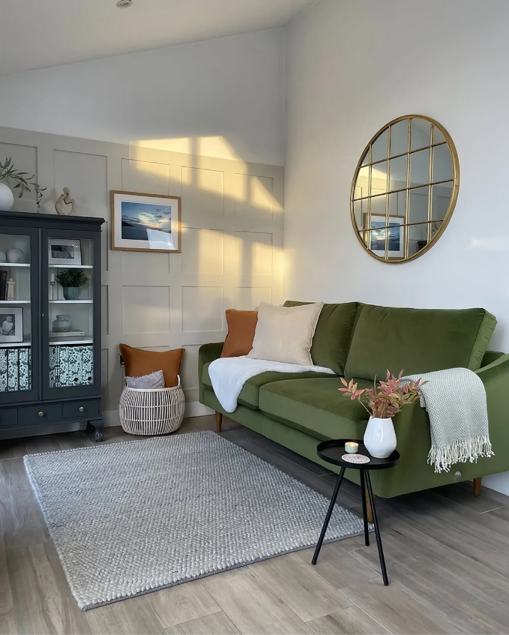 Olive green sofa with neutral pillows and soft gray decor in a bright living room