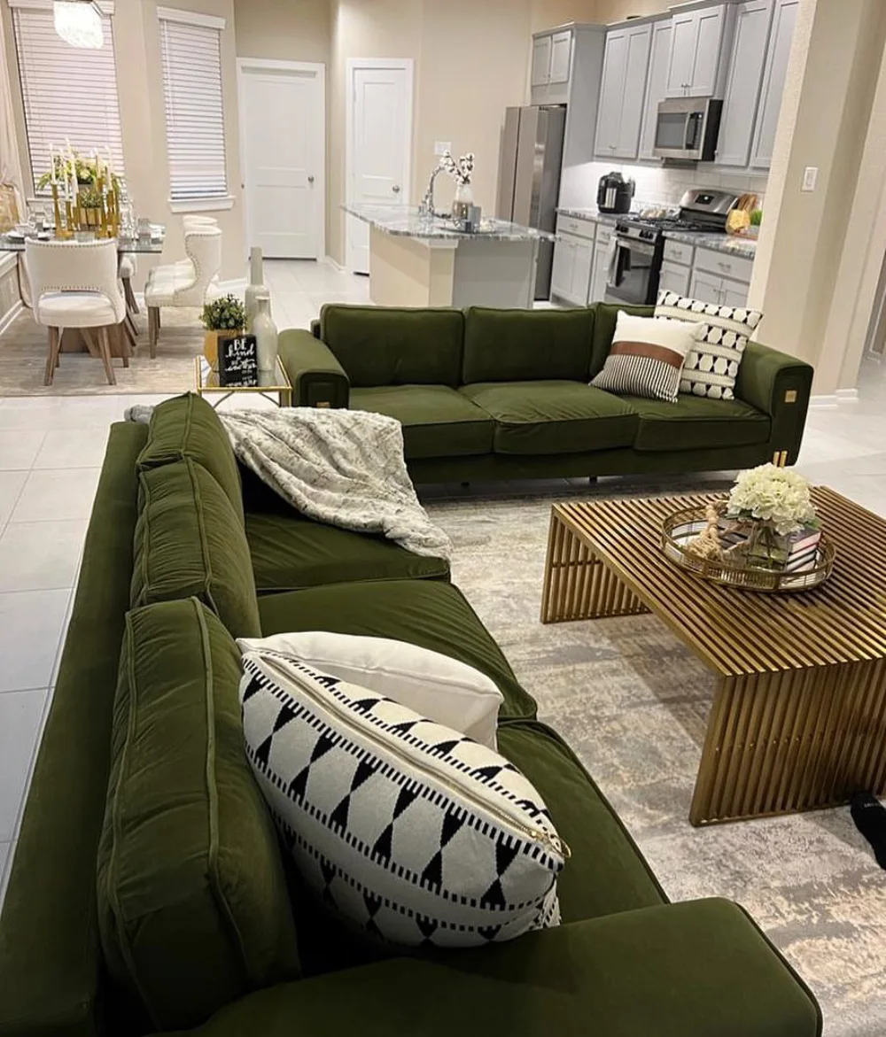 Dark olive green sofas arranged in an open-plan living room with a slatted wood coffee table