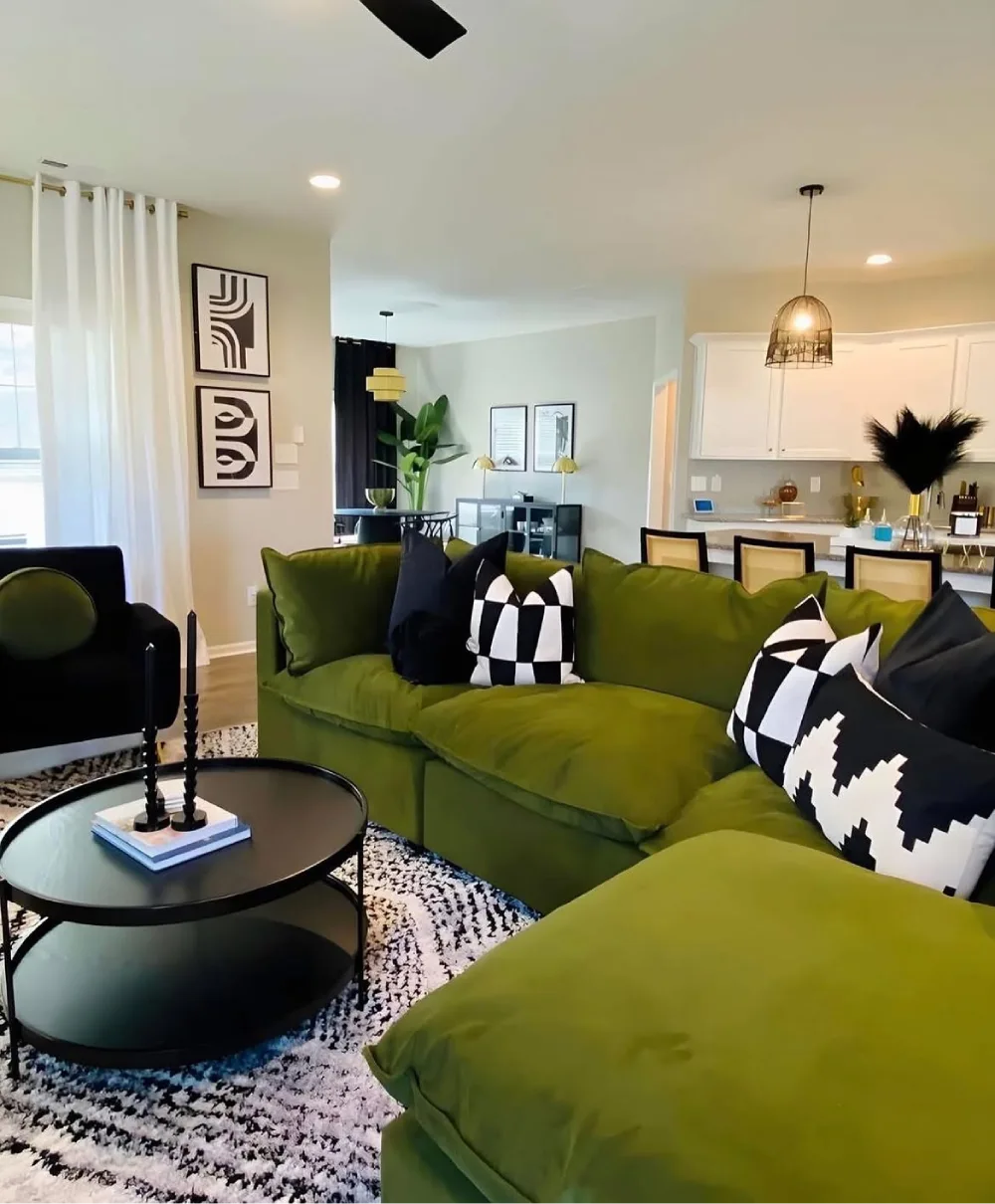 Olive green sectional sofa with black and white pillows in an open-plan living room