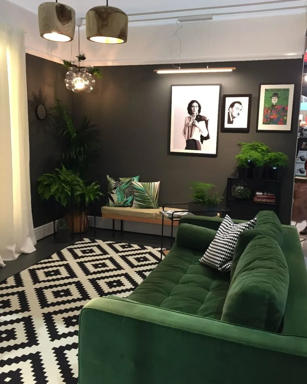 Deep green sofa in a moody living room with charcoal walls and patterned rug