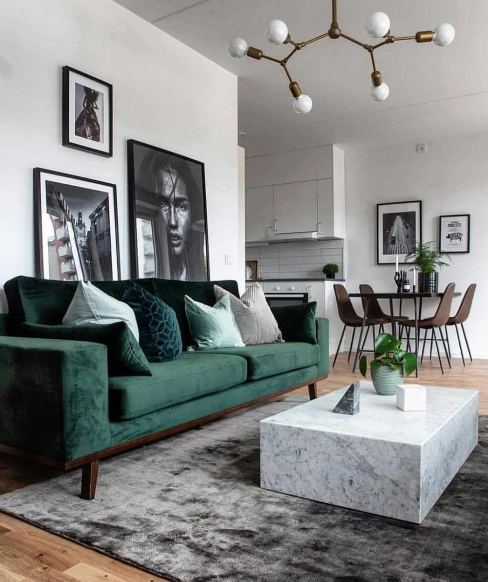 Deep green velvet sofa with marble coffee table in a modern open-plan living room