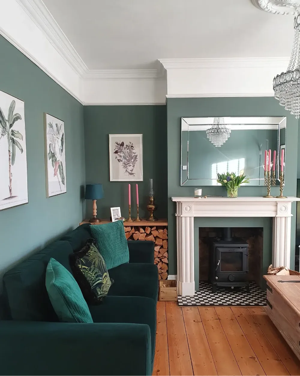 Deep teal green sofa in a living room with matching walls and colorful accents