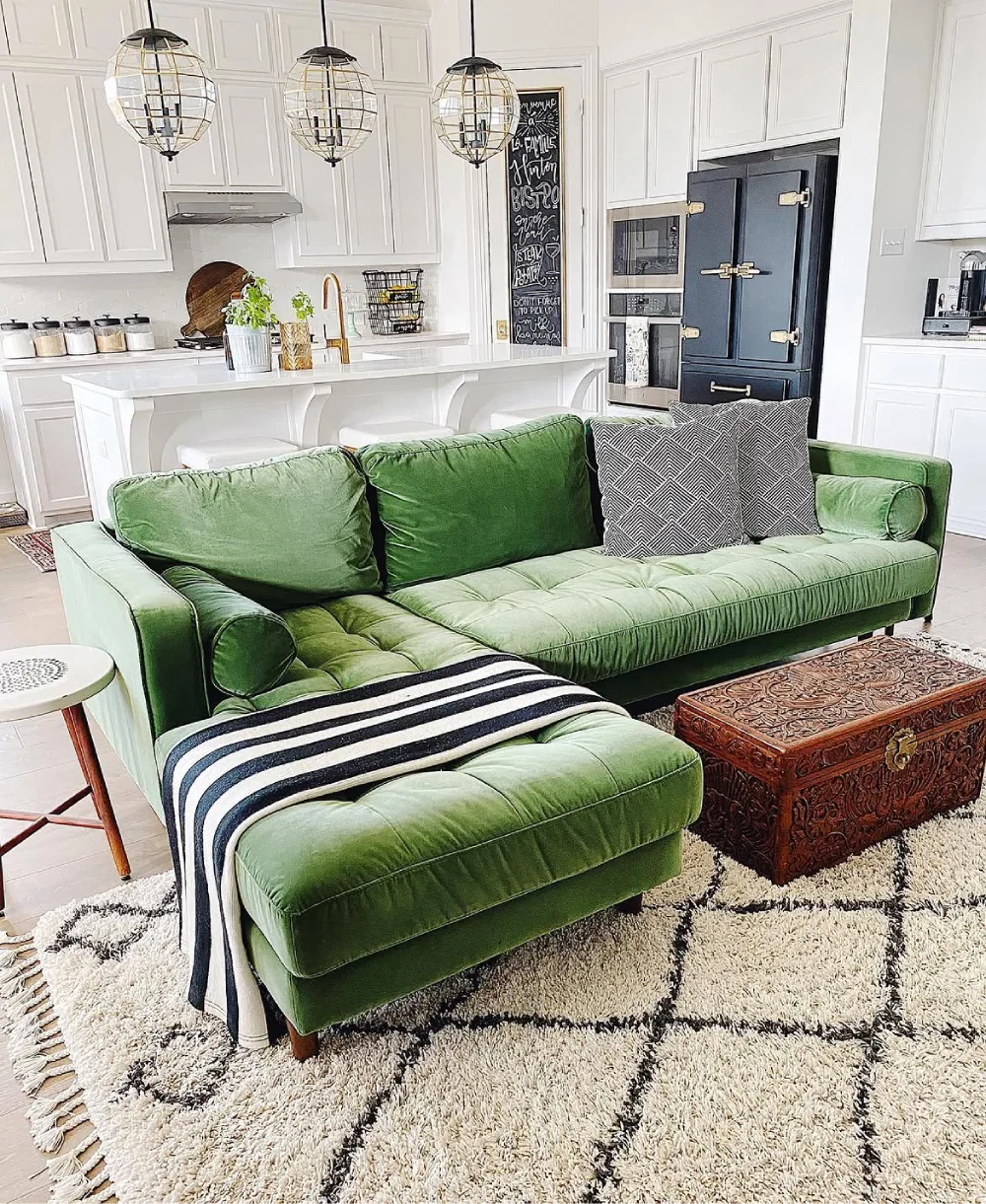 Light green sofa with patterned throw and vintage wooden chest in a bright living room