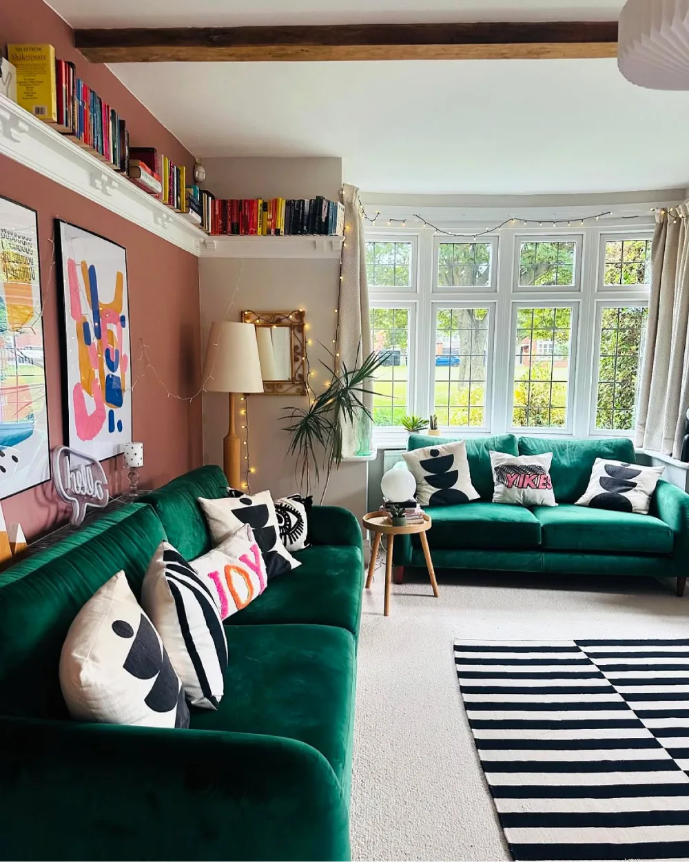Dark green sofas with colorful patterned pillows in an eclectic living room