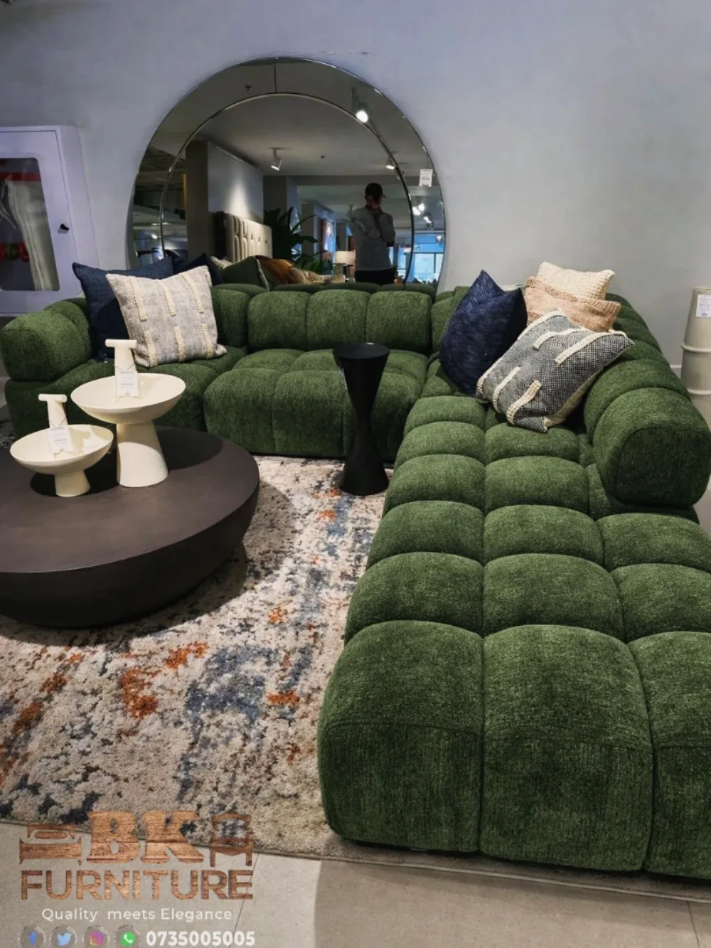 Deep green modular sectional sofa with layered pillows and a round coffee table