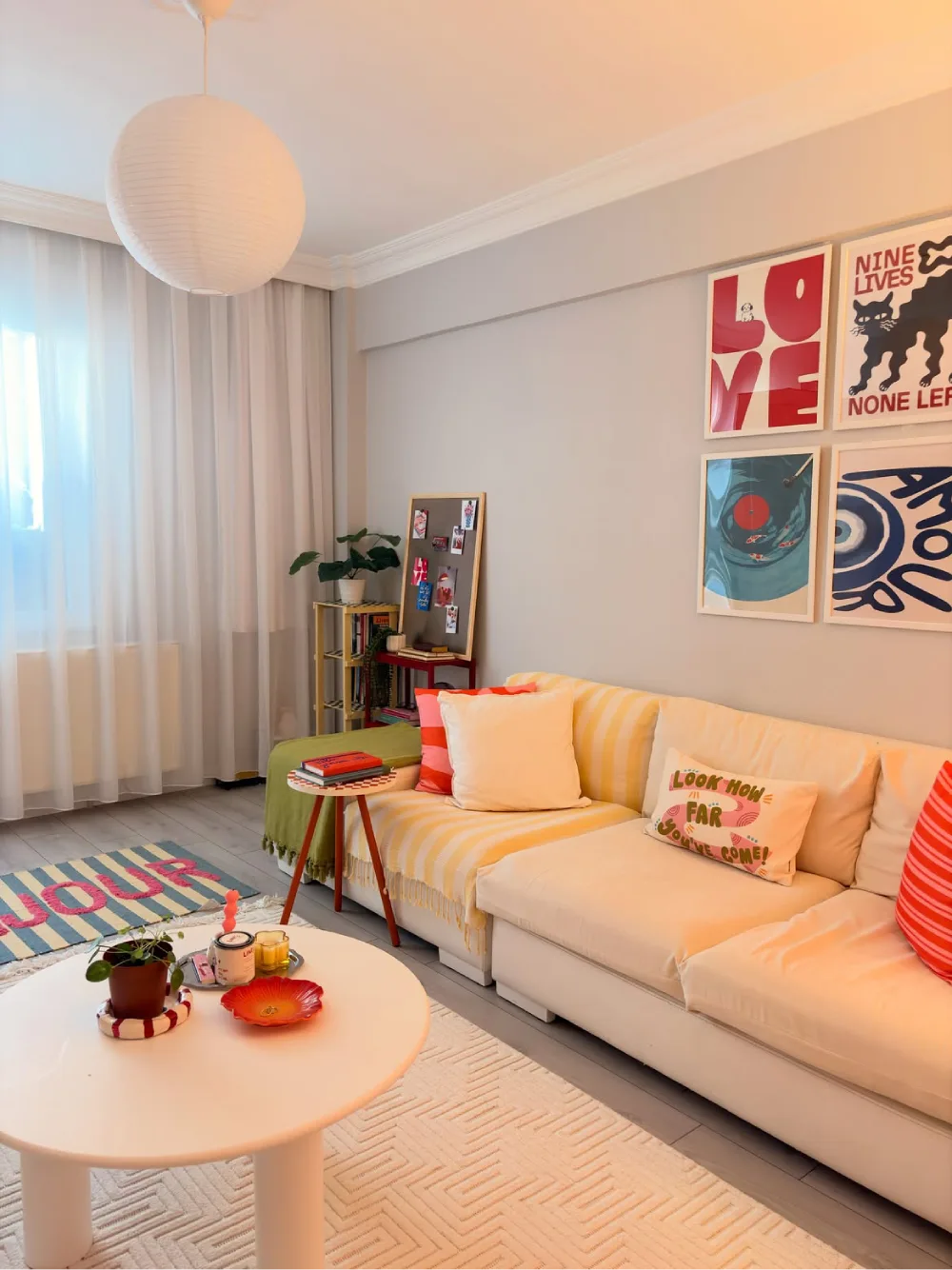 colorful living room with yellow accents, gallery wall, plants, and cream sectional sofa