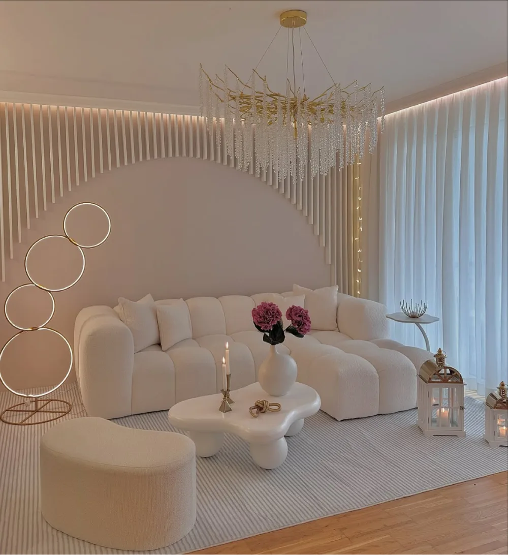 glamorous cream living room with curved sofa, sculptural coffee table, and crystal chandelier